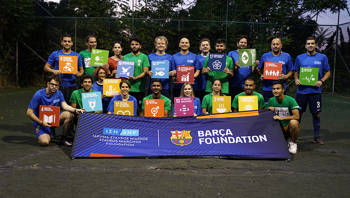 People dressed in soccer attire each hold up a sustainability goal on a soccer field